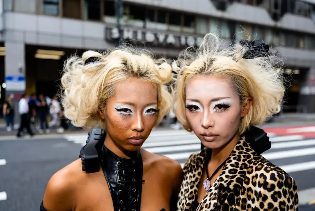ganguro gyaru girls deep tanned skin white eye makeup bleached blonde hair leopard print platform boots candid moment outside Shibuya 109 late 1990s Tokyo