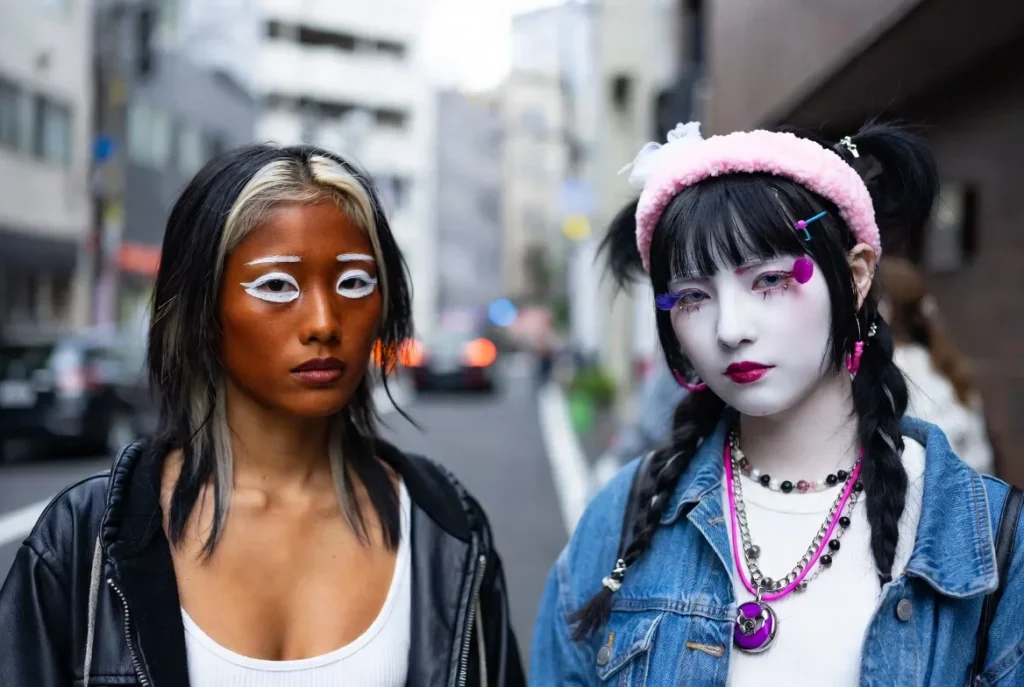 ganguro vs yamanba gyaru girls side by side deep tan white eye makeup larger white accents colorful accessories Tokyo street