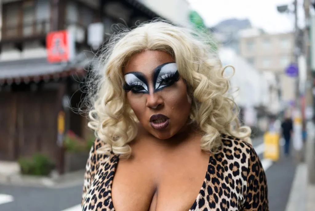 ganguro girl deep tan skin platinum blonde curls white eye makeup leopard print top mini skirt platform boots Tokyo street natural daylight